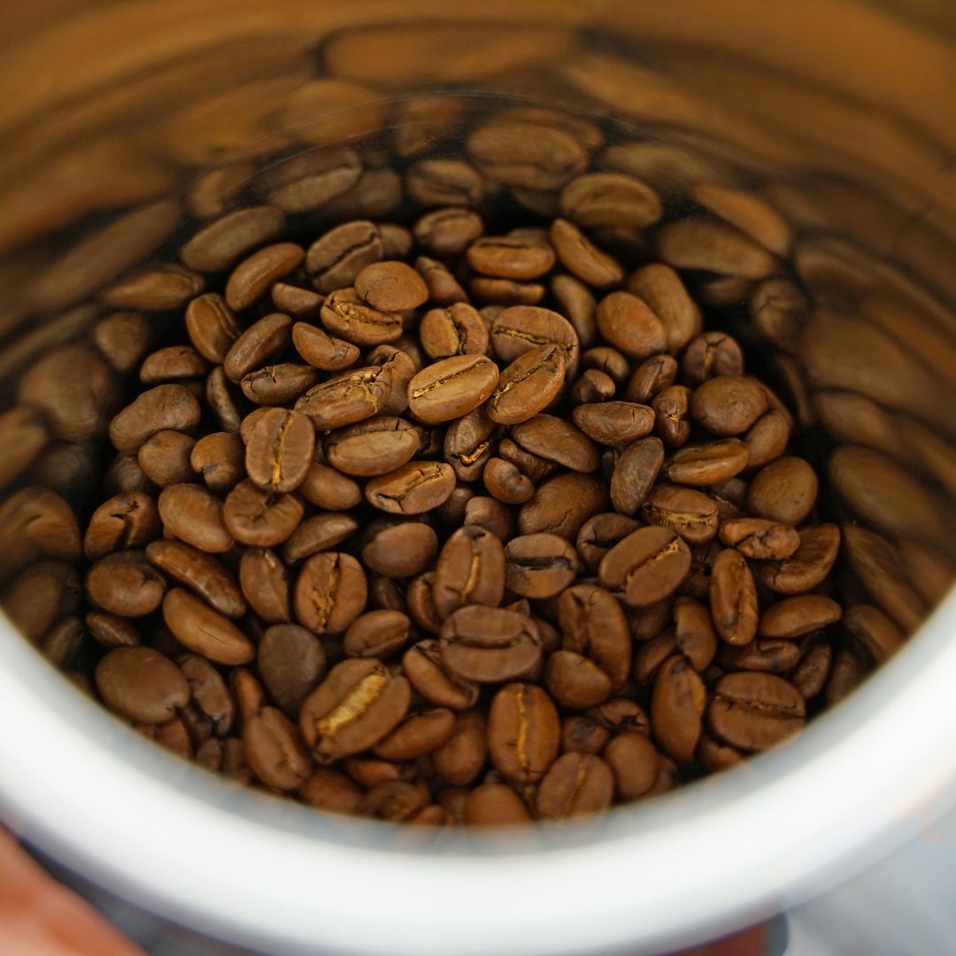 some well roasted coffee beans in a white cup